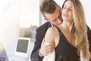 Young handsome man kissing young beautiful woman in the office